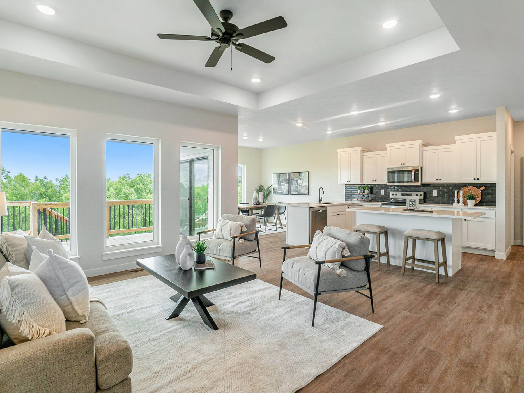 A bright, open living room and kitchen inside a new Empire Homes home in Sioux Falls, with large windows, a kitchen island and barstools